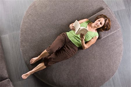 Woman lying on a round sofa and reading a book Stock Photo - Premium Royalty-Free, Code: 6108-05862874