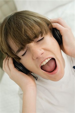 Boy listening to headphones and shouting Stock Photo - Premium Royalty-Free, Code: 6108-05862959