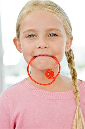 Portrait of a girl holding a candy in her mouth Stock Photo - Premium Royalty-Free, Code: 6108-05863080