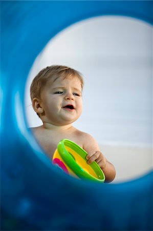 Baby boy playing with a toy viewed through an inflatable ring Stock Photo - Premium Royalty-Free, Code: 6108-05863147