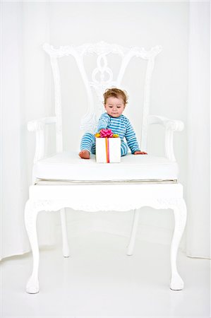 Baby boy sitting in an armchair with a gift Stock Photo - Premium Royalty-Free, Code: 6108-05863145