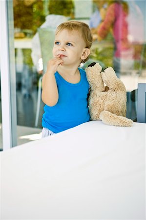 Baby boy holding a teddy bear and looking up Stock Photo - Premium Royalty-Free, Code: 6108-05863156