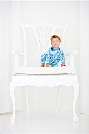 Baby boy sitting in an armchair and smiling Stock Photo - Premium Royalty-Free, Code: 6108-05863166