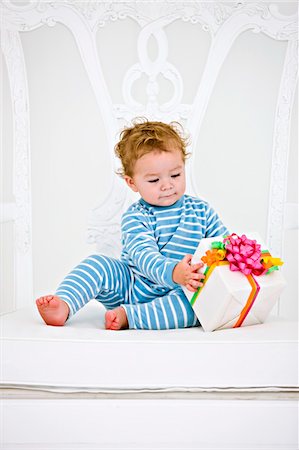 Baby boy playing with a present in an armchair Stock Photo - Premium Royalty-Free, Code: 6108-05863168
