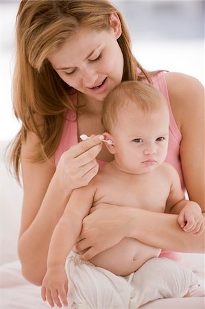 Femme oreille de sa fille avec un cotton-tige de nettoyage Photographie de stock - Premium Libres de Droits, Code: 6108-05863175