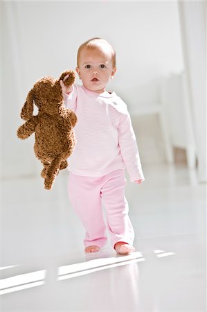 Baby girl walking on the floor with a toy Stock Photo - Premium Royalty-Free, Code: 6108-05863119