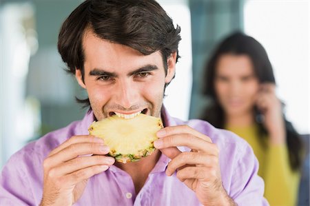 Man eating a pineapple slice Stock Photo - Premium Royalty-Free, Code: 6108-05863261