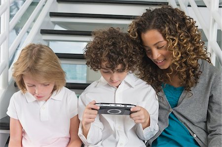 Boy playing a video game with his sisters Stock Photo - Premium Royalty-Free, Code: 6108-05863399