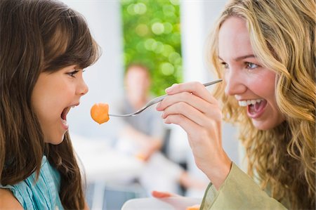 Woman feeding fruit salad to her daughter Foto de stock - Sin royalties Premium, Código: 6108-05863441