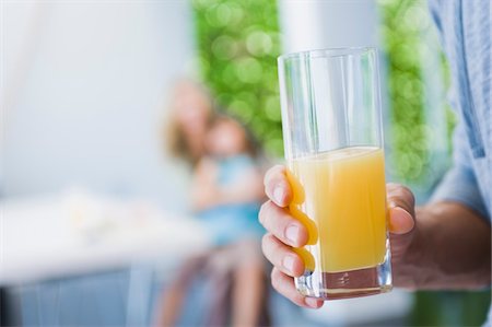 Man's hand holding a glass of juice Stock Photo - Premium Royalty-Free, Code: 6108-05863476