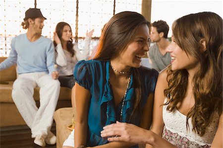 Deux femmes souriant avec leurs amis en arrière-plan Photographie de stock - Premium Libres de Droits, Code: 6108-05863671