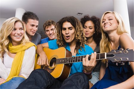 Man sitting with his friends and playing a guitar Stock Photo - Premium Royalty-Free, Code: 6108-05863638