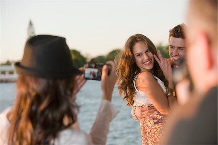 Woman taking a picture of her friends with a camera Stock Photo - Premium Royalty-Free, Code: 6108-05863727