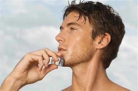 Man rubbing an ice cube on his face Stock Photo - Premium Royalty-Free, Code: 6108-05863888