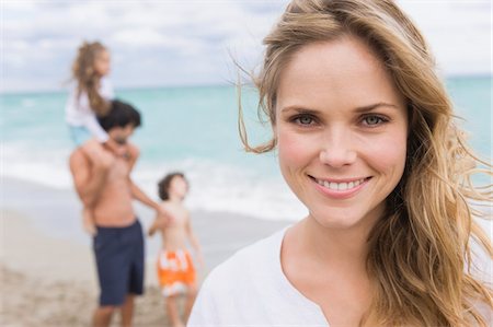 Femme souriant avec sa famille en arrière-plan Photographie de stock - Premium Libres de Droits, Code: 6108-05864040