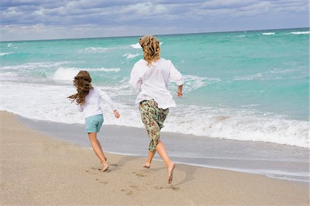 Woman running with her daughter on the beach Stock Photo - Premium Royalty-Free, Code: 6108-05864066