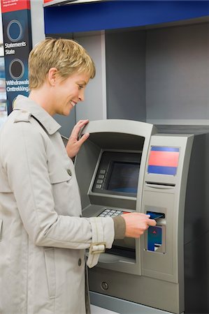 Woman inserting a credit card into ATM Stock Photo - Premium Royalty-Free, Code: 6108-05864552