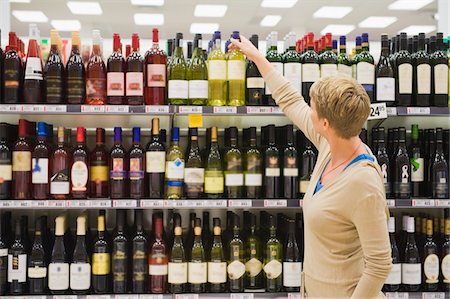 simsearch:877-06835434,k - Woman choosing wine bottle in a supermarket Fotografie stock - Premium Royalty-Free, Codice: 6108-05864516