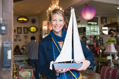 Woman holding a toy boat in a store Stock Photo - Premium Royalty-Free, Code: 6108-05864692