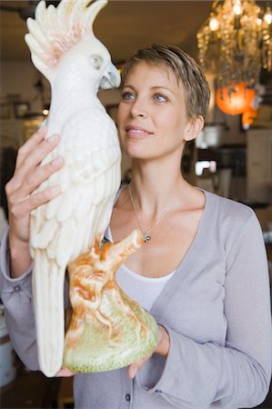 papagaio (pássaro) - Woman holding a statue of a parrot in a store Foto de stock - Royalty Free Premium, Número: 6108-05864719