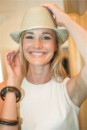 simsearch:6108-05864781,k - Woman trying on a fedora in a boutique and smiling Stock Photo - Premium Royalty-Free, Code: 6108-05864864