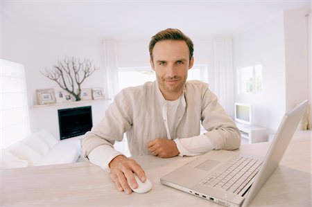 Portrait of a man working on a laptop and smiling Stock Photo - Premium Royalty-Free, Code: 6108-05865034