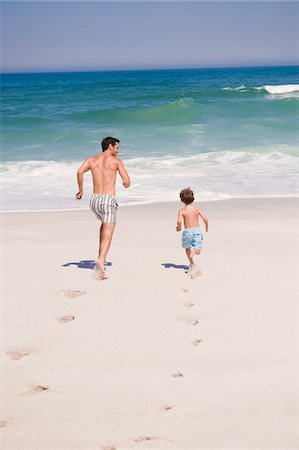 Man running with his son on the beach Stock Photo - Premium Royalty-Free, Code: 6108-05865172