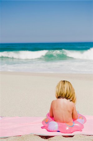 sitting inner tube - Girl sitting with an inflatable ring on the beach Stock Photo - Premium Royalty-Free, Code: 6108-05865175