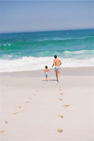 Man running with his son on the beach Stock Photo - Premium Royalty-Free, Code: 6108-05865182