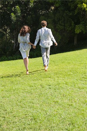 Rear view of a couple running on grass Stock Photo - Premium Royalty-Free, Code: 6108-05865116