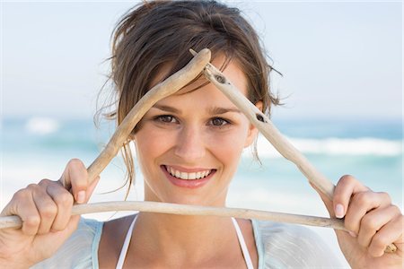 signage on the beach - Woman making triangle shape with sticks Stock Photo - Premium Royalty-Free, Code: 6108-05865252