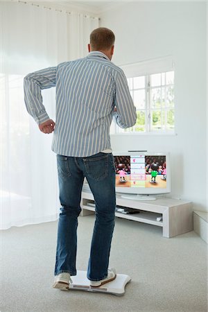 Man doing step aerobics and watching TV Stock Photo - Premium Royalty-Free, Code: 6108-05865287