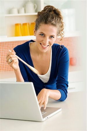 Portrait of a woman working on a laptop in the kitchen Stock Photo - Premium Royalty-Free, Code: 6108-05865386