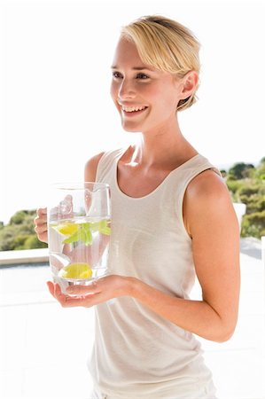 Woman holding a jug of lemonade and smiling Stock Photo - Premium Royalty-Free, Code: 6108-05865339