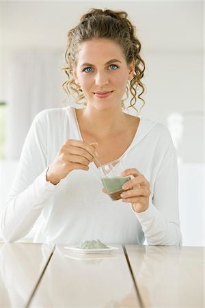Portrait of a woman mixing green clay for facial mask Stock Photo - Premium Royalty-Free, Code: 6108-05865470