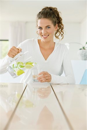 fruit drinks lemon - Woman pouring lemonade into a glass from a jug Stock Photo - Premium Royalty-Free, Code: 6108-05865494