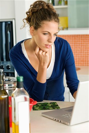 simsearch:6108-05865429,k - Femme lisant une recette sur un ordinateur portable dans la cuisine Photographie de stock - Premium Libres de Droits, Code: 6108-05865432