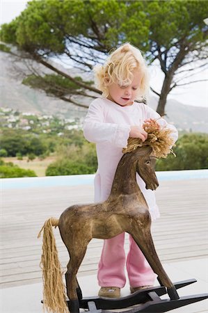 Girl playing with a rocking horse Stock Photo - Premium Royalty-Free, Code: 6108-05865588