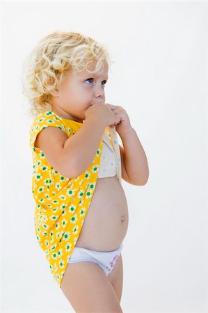 Three small girls standing outside in underwear, rear view, b&w