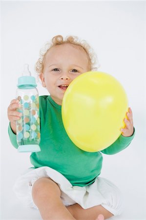 Baby boy holding a balloon and a baby bottle Stock Photo - Premium Royalty-Free, Code: 6108-05865642