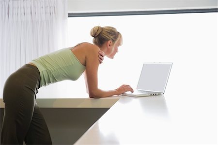 simsearch:6108-05859712,k - Woman leaning on a counter and working on a laptop Foto de stock - Royalty Free Premium, Número: 6108-05865775