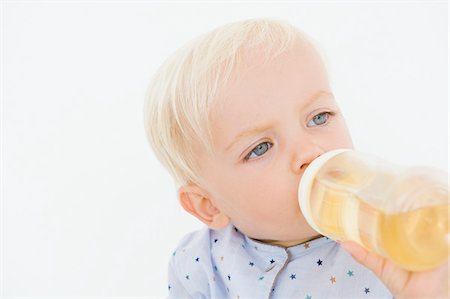 Baby boy drinking juice from a baby bottle Stock Photo - Premium Royalty-Free, Code: 6108-05865705