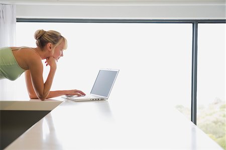 simsearch:6108-05859712,k - Woman leaning on a counter and working on a laptop Foto de stock - Royalty Free Premium, Número: 6108-05865728