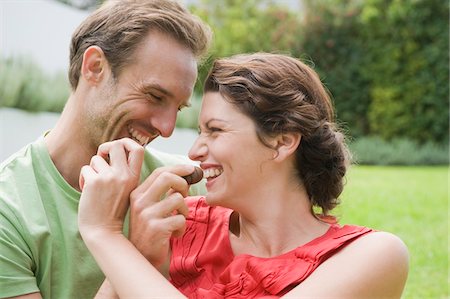 Couple feeding chocolates to each other and smiling Stock Photo - Premium Royalty-Free, Code: 6108-05865867