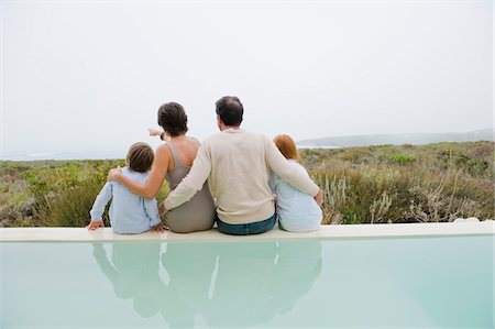 someone pointing at a group of people - Family sitting at the poolside Stock Photo - Premium Royalty-Free, Code: 6108-05865823