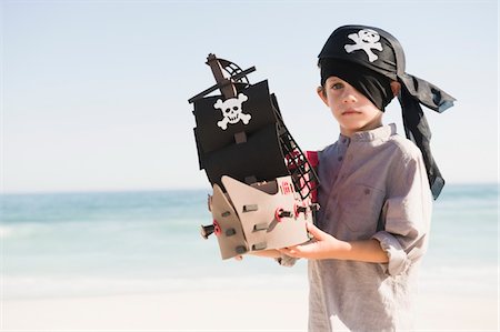 pirate - Boy in pirate costume playing with a toy boat Stock Photo - Premium Royalty-Free, Code: 6108-05865967