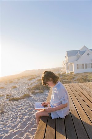 Girl sitting on a boardwalk and reading a book Stock Photo - Premium Royalty-Free, Code: 6108-05865902