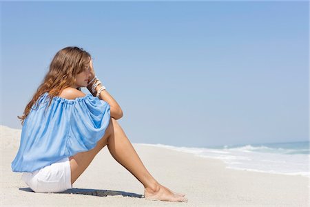 Woman sitting on the beach and thinking Stock Photo - Premium Royalty-Free, Code: 6108-05866065