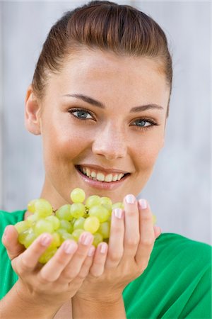 Woman holding bunch of grapes and smiling Stock Photo - Premium Royalty-Free, Code: 6108-05866166