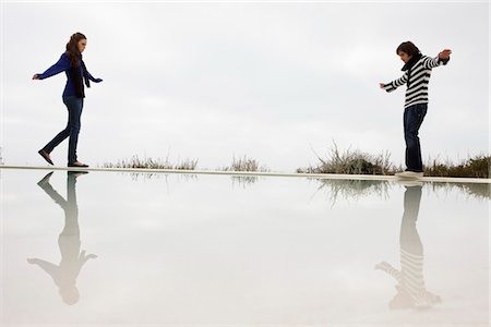 Couple walking on the ledge of a swimming pool Stock Photo - Premium Royalty-Free, Code: 6108-05866182